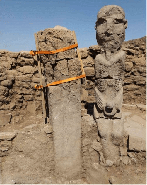 The Karahan Tepe male 'ribbed man' statue standing in situ beside a pillar